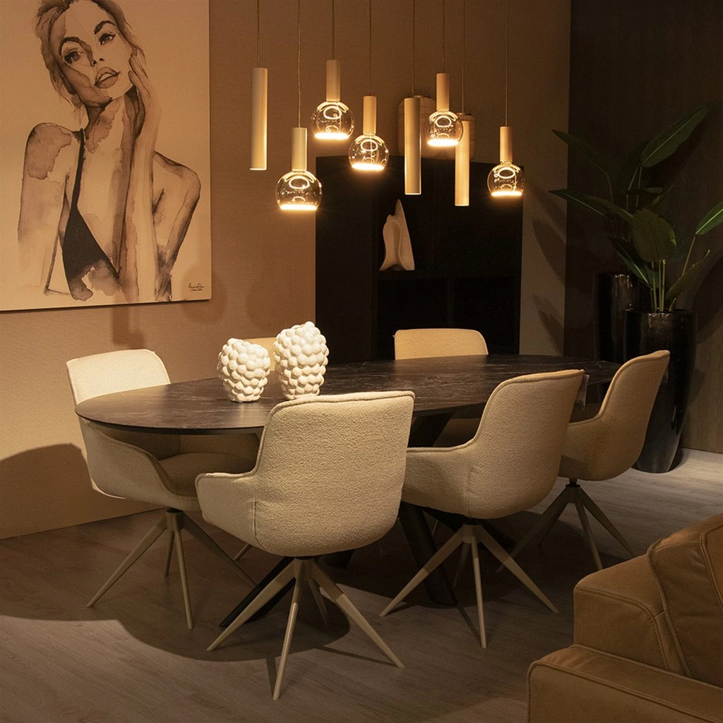 Zandkleurige hanglampen van Straluma boven een ovale eettafel met beige eetkamerstoelen in een warme, moderne eetkamer.