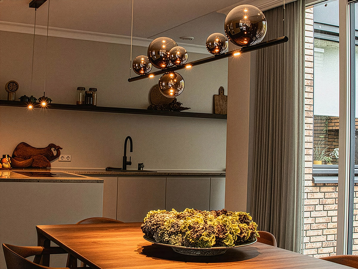 Moderne hanglamp met glazen bollen boven een houten eettafel in een sfeervolle keuken – Straluma.