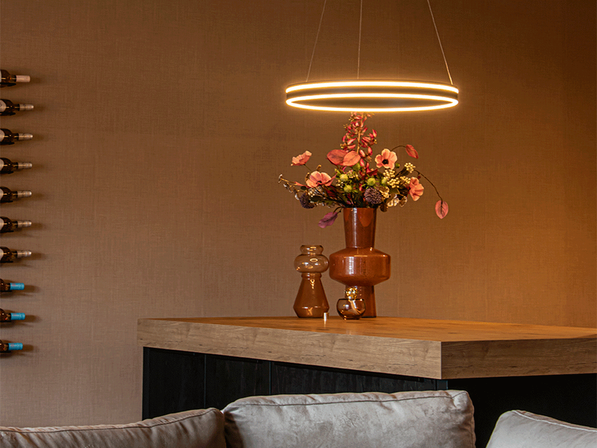 Moderne ronde LED-hanglamp boven een houten bartafel met keramische vaas – interieurverlichting van Straluma