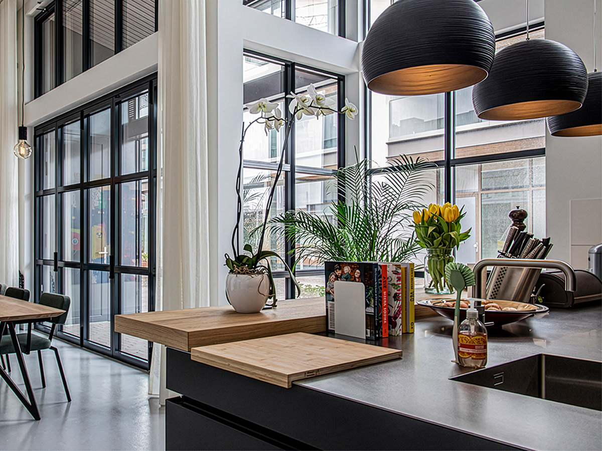 Moderne keuken met grote zwarte hanglampen, veel daglicht en groene planten – interieurinspiratie van Straluma.