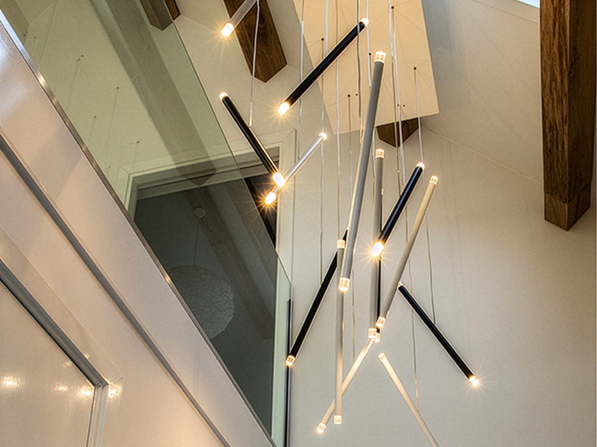 Moderne videlamp met meerdere LED-staven in een hoge vide, interieurfotografie Straluma.