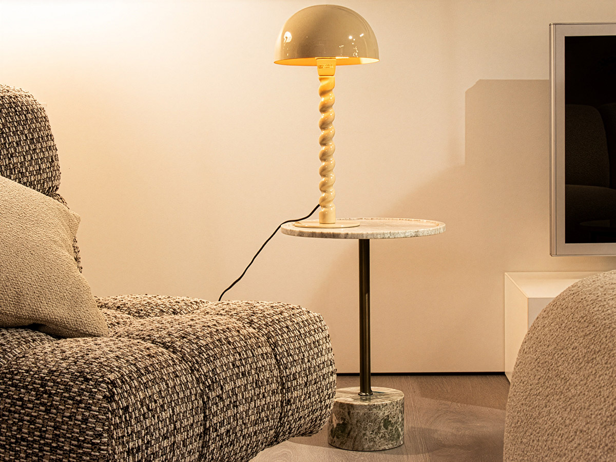 Moderne tafellamp op marmeren bijzettafel naast een zachte design bank in warme woonkamer