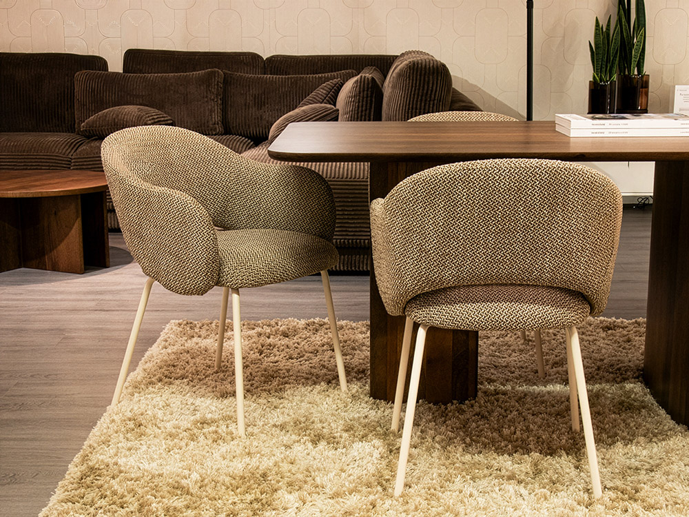 Moderne eetkamer met zachte stoffen eetkamerstoelen en houten tafel op hoogpolig vloerkleed