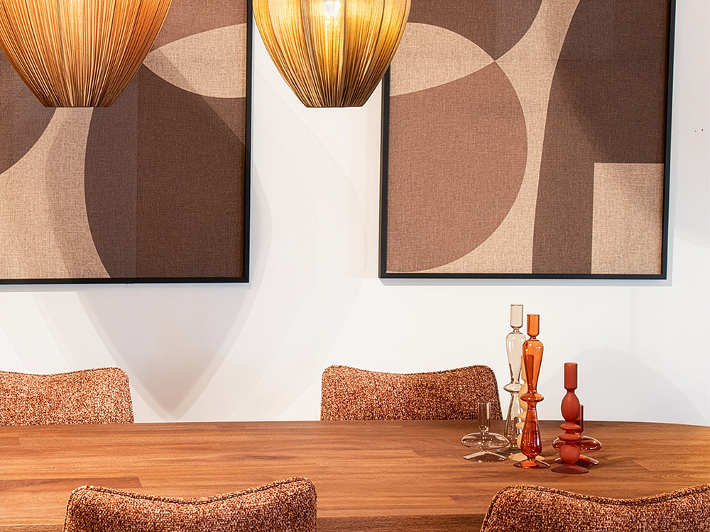 Eettafel met warme gestoffeerde eetkamerstoelen, moderne hanglampen en gekleurde kandelaars in stijlvol interieur