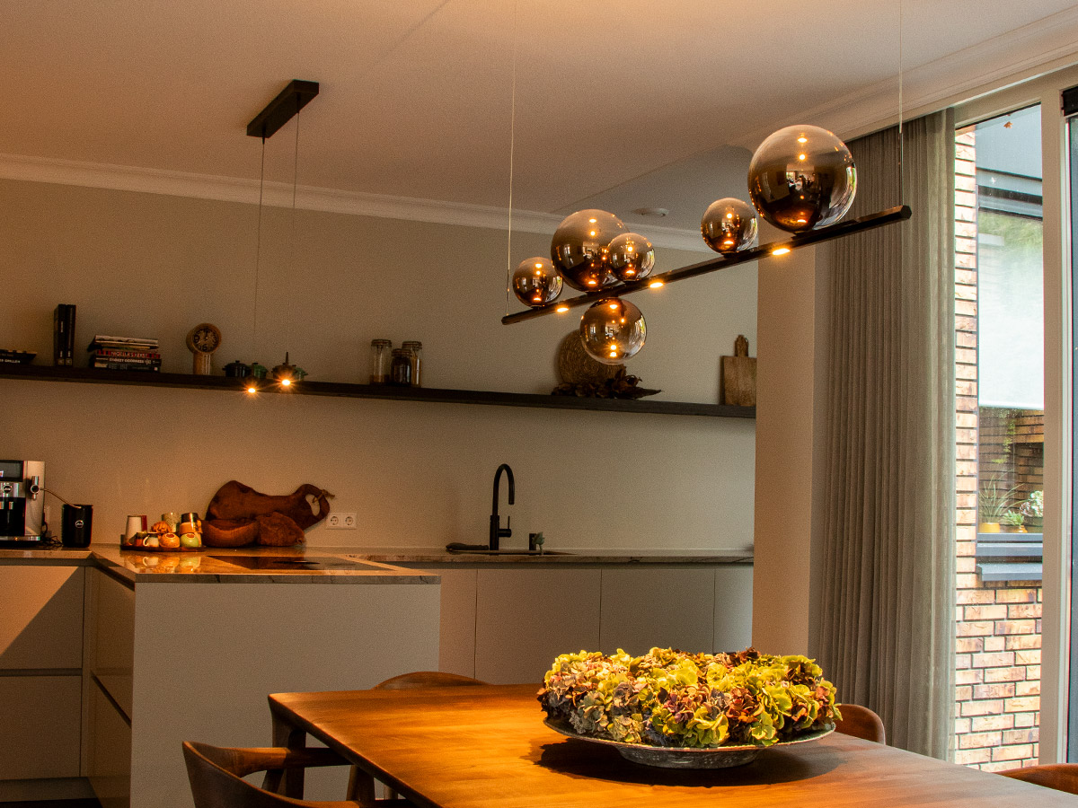 Moderne hanglamp met glazen bollen boven eettafel in luxe keuken van een woonhuis in Hendrik-Ido-Ambacht, geplaatst door Straluma.