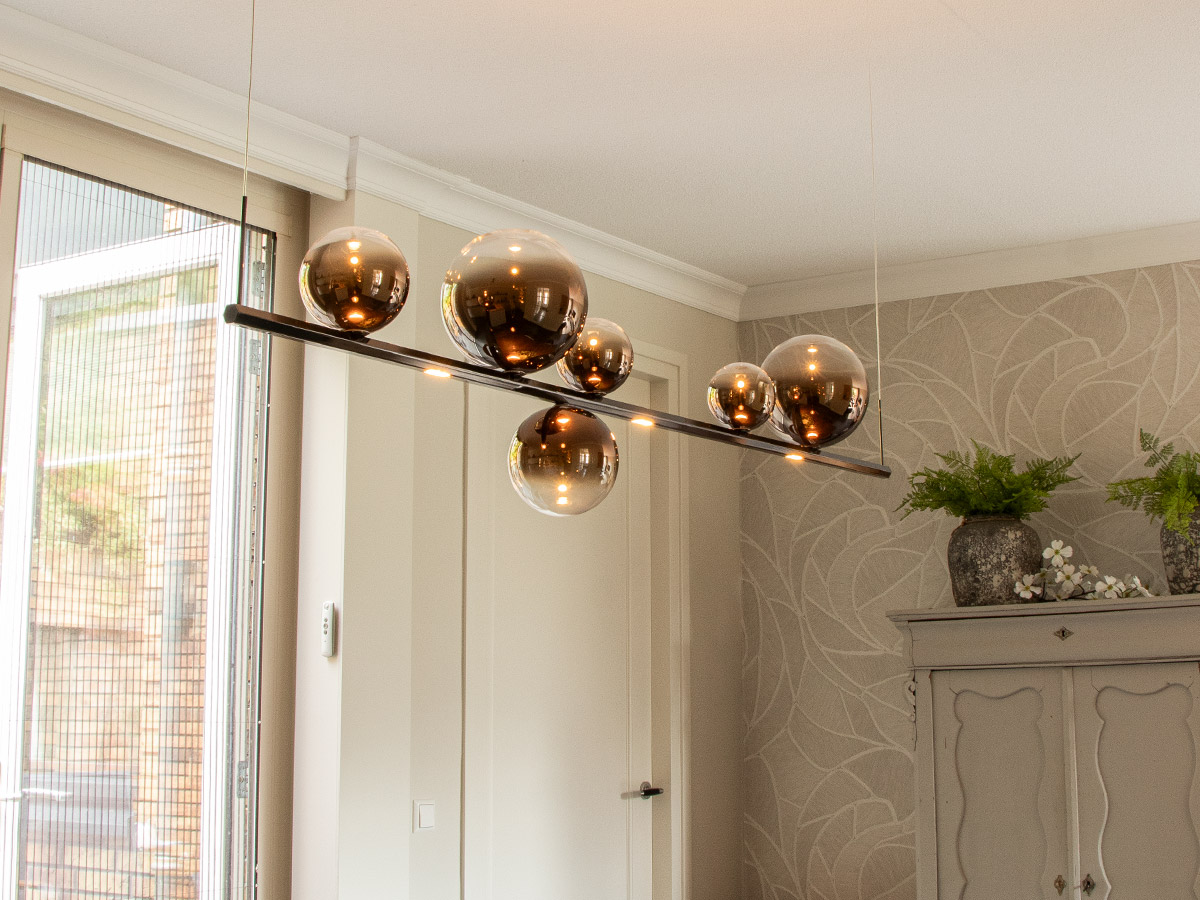 Moderne hanglamp met rookglazen bollen boven de eettafel in een stijlvolle woonkamer in Hendrik-Ido-Ambacht, geplaatst door Straluma.
